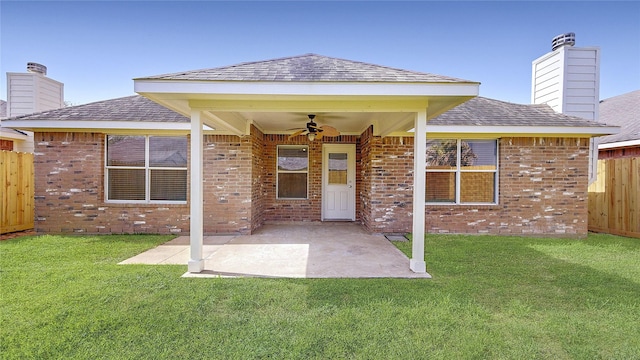 back of property with a chimney, fence, brick siding, and a yard