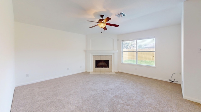 unfurnished living room featuring a tile fireplace, light carpet, baseboards, visible vents, and ceiling fan