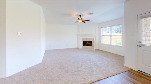 unfurnished living room featuring carpet, baseboards, visible vents, a ceiling fan, and a fireplace