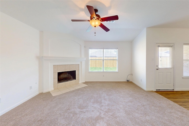 unfurnished living room featuring baseboards, a fireplace, ceiling fan, and carpet flooring