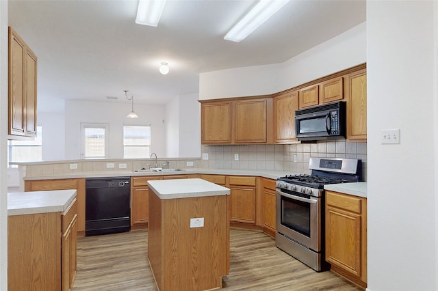 kitchen with a sink, black appliances, light wood-style floors, and tasteful backsplash