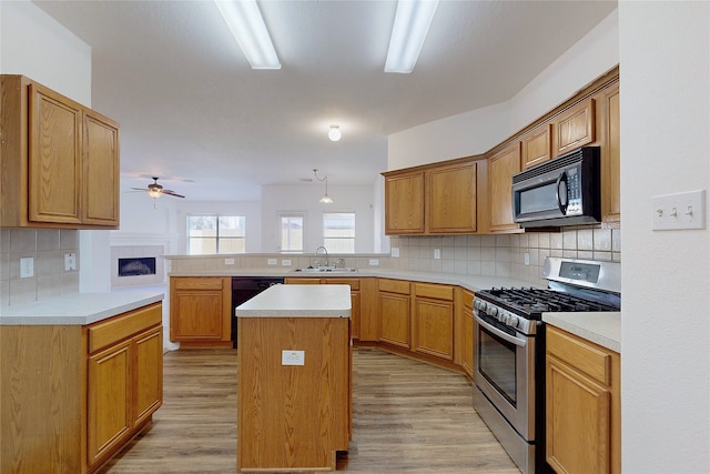 kitchen with light countertops, a sink, a ceiling fan, a peninsula, and black appliances