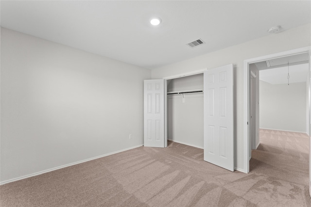 unfurnished bedroom with attic access, carpet, visible vents, and a closet