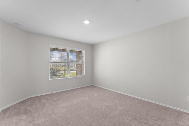 spare room with light colored carpet and baseboards