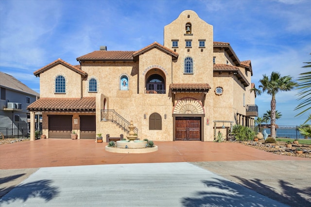 view of front of house featuring an attached garage, stucco siding, fence, and a tile roof