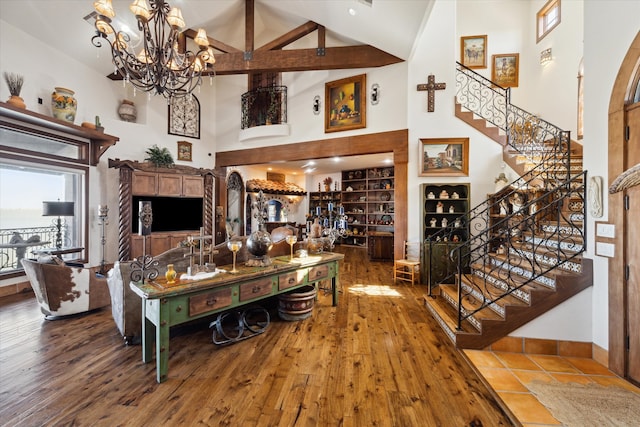 living room with high vaulted ceiling, stairs, hardwood / wood-style flooring, and an inviting chandelier