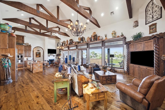 living area featuring visible vents, an inviting chandelier, beam ceiling, wood-type flooring, and high vaulted ceiling