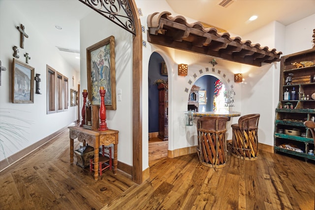 wine area featuring baseboards, recessed lighting, visible vents, arched walkways, and wood-type flooring