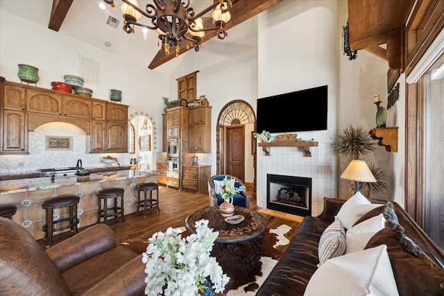 living area with beamed ceiling, visible vents, a chandelier, dark wood-style flooring, and a tile fireplace