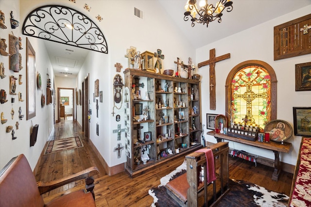 corridor featuring visible vents, baseboards, attic access, vaulted ceiling, and hardwood / wood-style floors