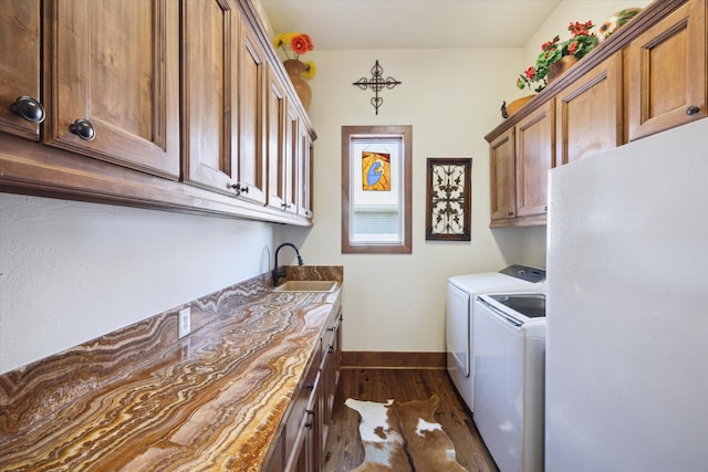 laundry room with dark wood-style flooring, baseboards, independent washer and dryer, cabinet space, and a sink