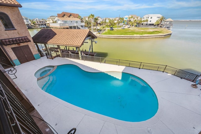 view of pool with a water view, a residential view, a pool with connected hot tub, and fence