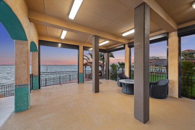 view of patio with fence and a water view
