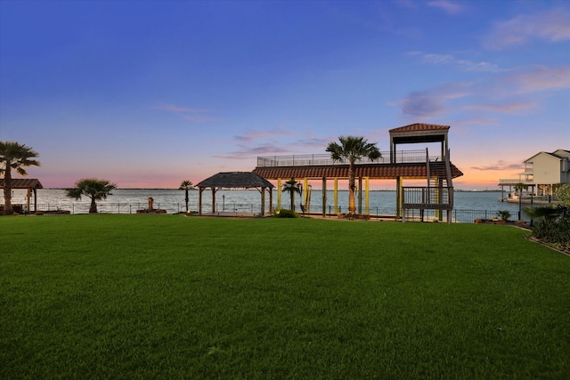 yard at dusk featuring a water view and a gazebo