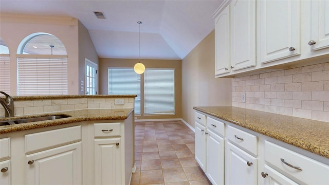 kitchen featuring visible vents, backsplash, pendant lighting, vaulted ceiling, and a sink