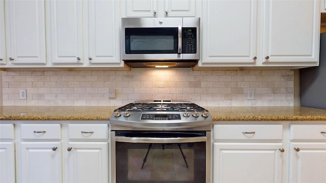 kitchen with stainless steel appliances, light stone countertops, tasteful backsplash, and white cabinetry