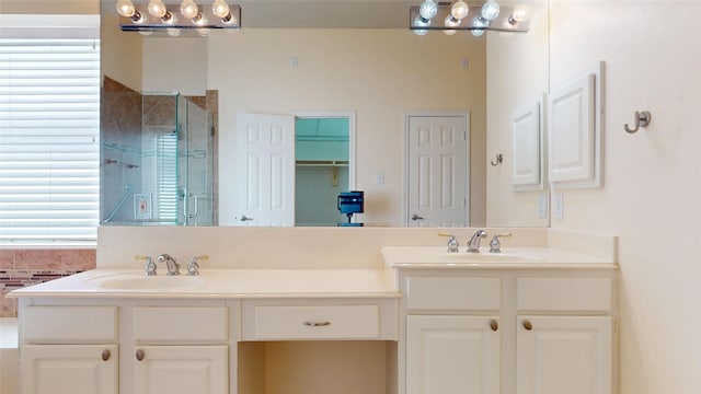 bathroom with double vanity, a shower stall, and a sink