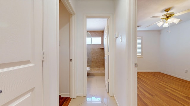 corridor with baseboards and light wood finished floors