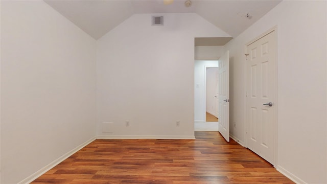 empty room featuring vaulted ceiling, wood finished floors, visible vents, and baseboards