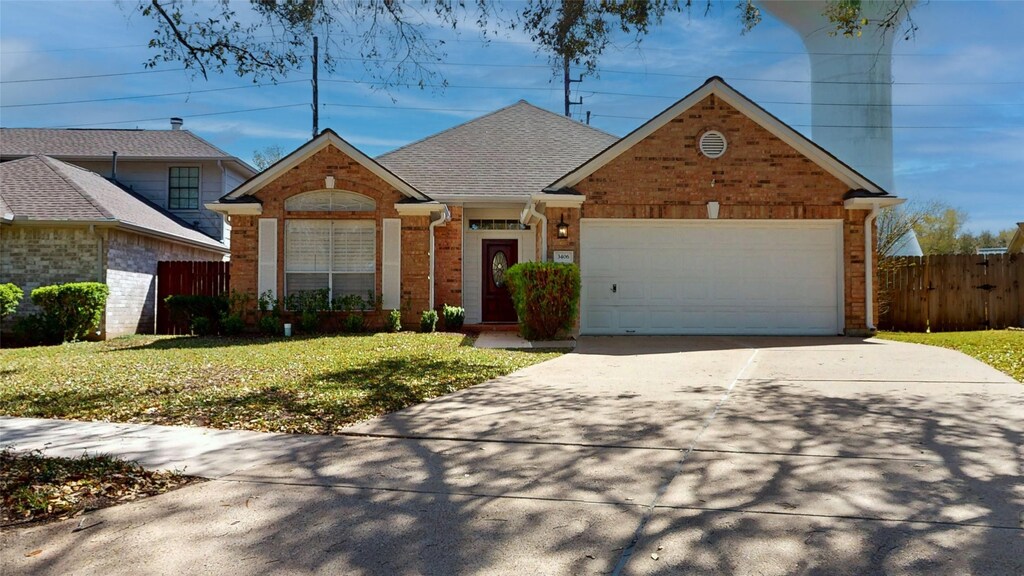 3406 Honey Creek Dr, Sugar Land, TX 77478 - view of front of home with fence, concrete driveway, a front lawn, a garage, and brick siding