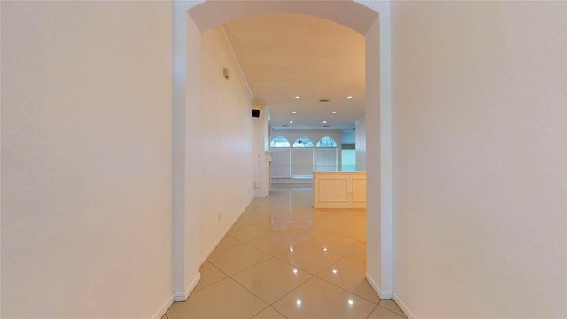 corridor with tile patterned floors, baseboards, arched walkways, and recessed lighting