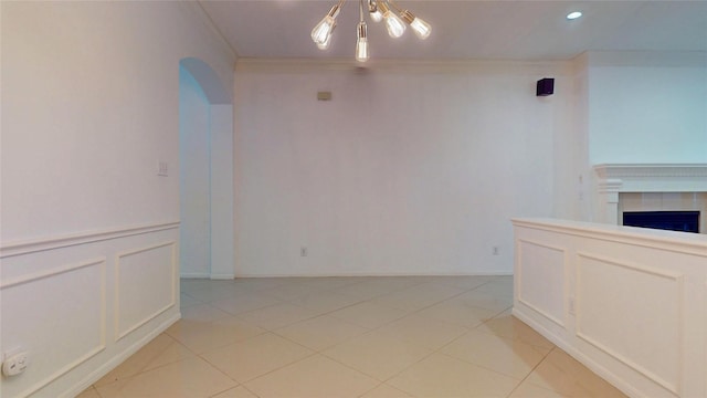 interior space with light tile patterned floors, a decorative wall, a fireplace, and ornamental molding