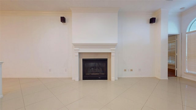 unfurnished living room featuring light tile patterned flooring, a fireplace, baseboards, and ornamental molding