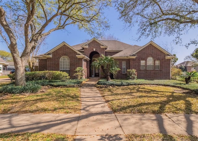 ranch-style home with a front yard and brick siding