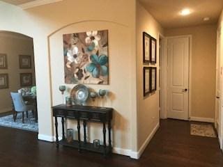 hallway featuring baseboards, arched walkways, and wood finished floors