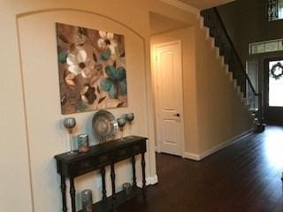foyer featuring dark wood-type flooring, stairs, and baseboards