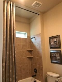 bathroom featuring visible vents, shower / bath combination with curtain, and toilet