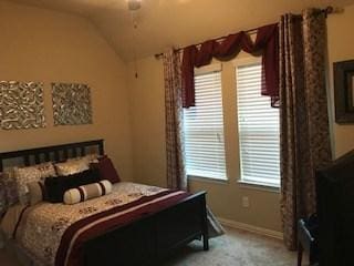 carpeted bedroom featuring a ceiling fan, vaulted ceiling, and baseboards