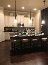 kitchen with a breakfast bar, pendant lighting, dark countertops, and stainless steel microwave