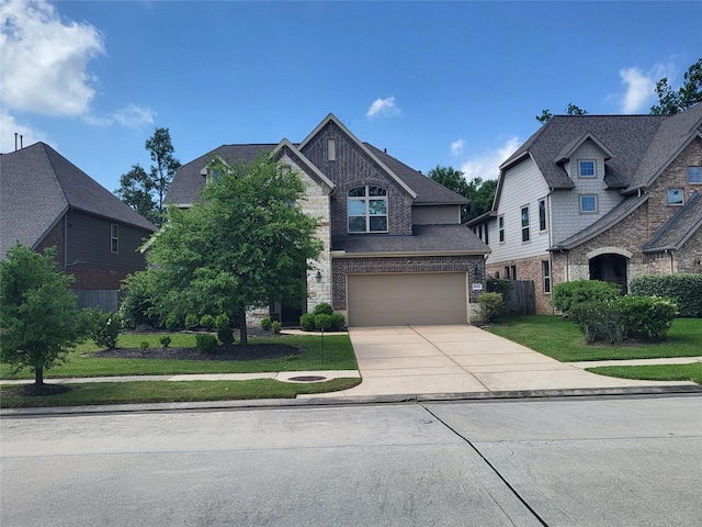 view of front of house featuring a front lawn, driveway, brick siding, an attached garage, and fence