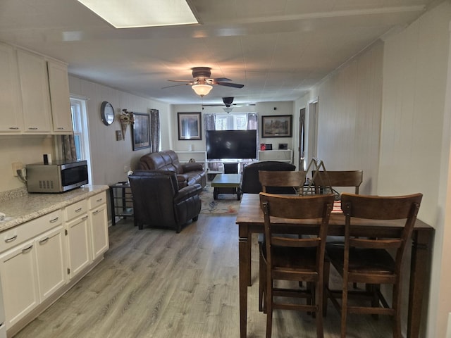 dining area with light wood-type flooring and a ceiling fan