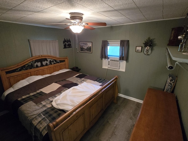 bedroom featuring dark wood-type flooring, baseboards, ornamental molding, cooling unit, and a ceiling fan