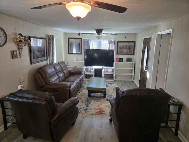 living area featuring wood walls, ceiling fan, and wood finished floors