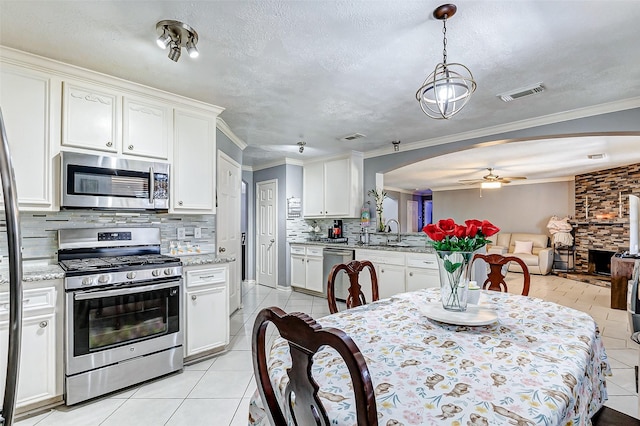 dining room featuring visible vents, arched walkways, crown molding, light tile patterned floors, and ceiling fan