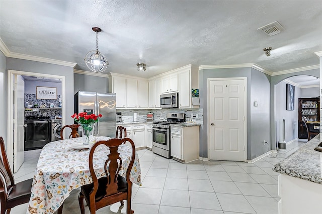 kitchen with arched walkways, appliances with stainless steel finishes, light tile patterned flooring, and separate washer and dryer