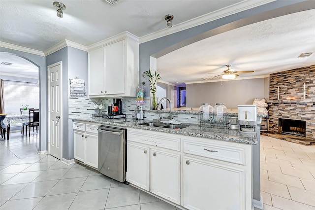 kitchen with a sink, a peninsula, light tile patterned flooring, arched walkways, and stainless steel dishwasher