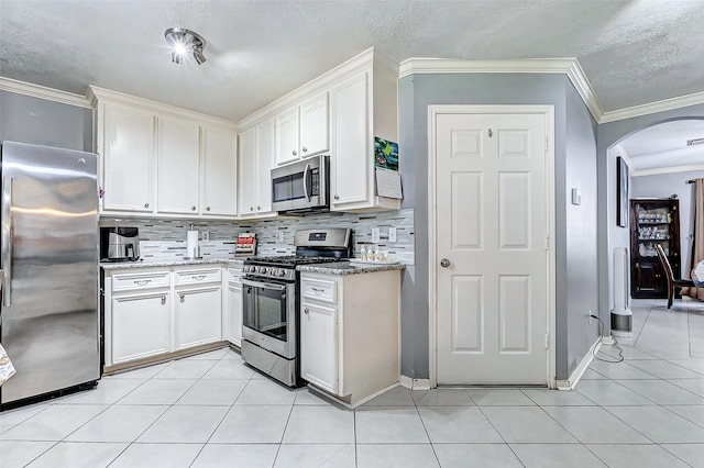 kitchen featuring light tile patterned floors, stainless steel appliances, and arched walkways