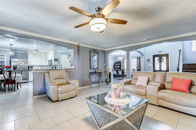 living area featuring visible vents, a ceiling fan, a textured ceiling, arched walkways, and light tile patterned flooring