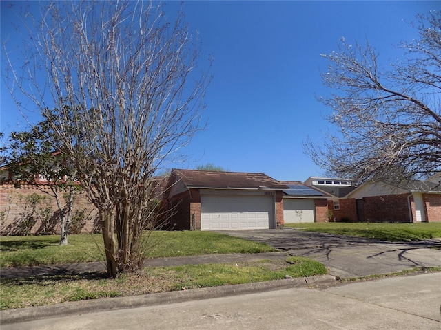 view of front of property with a front yard, an attached garage, brick siding, and driveway