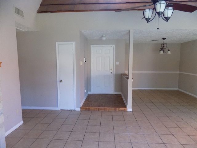 interior space featuring a ceiling fan, baseboards, visible vents, light tile patterned flooring, and a textured ceiling