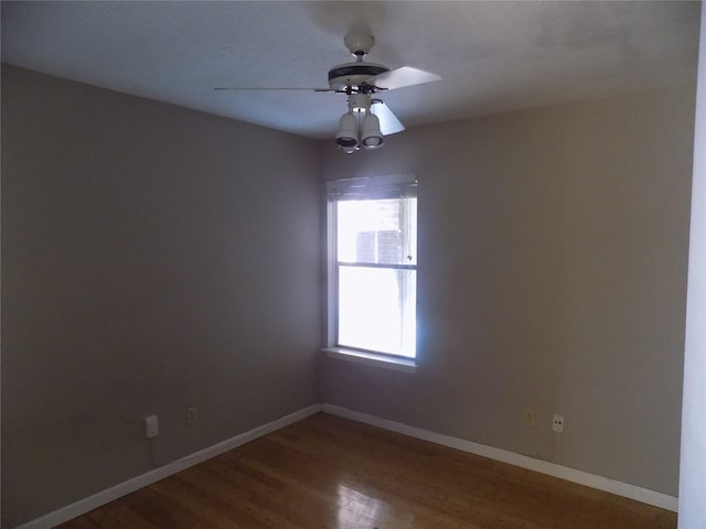 spare room featuring baseboards, wood finished floors, and a ceiling fan