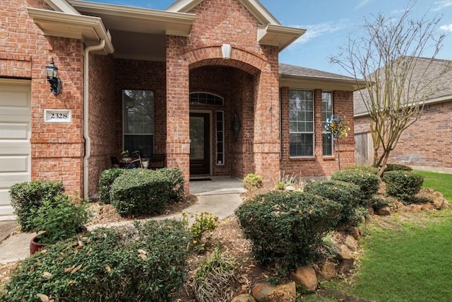 view of exterior entry featuring brick siding and an attached garage