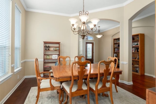 dining area with baseboards, arched walkways, an inviting chandelier, and wood finished floors