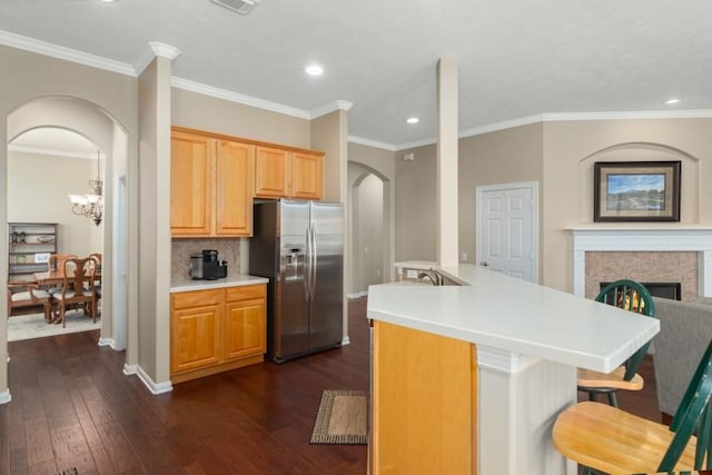 kitchen with stainless steel fridge with ice dispenser, dark wood finished floors, a breakfast bar area, decorative backsplash, and arched walkways