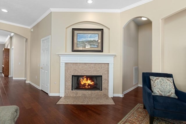 living room with baseboards, arched walkways, wood finished floors, and ornamental molding