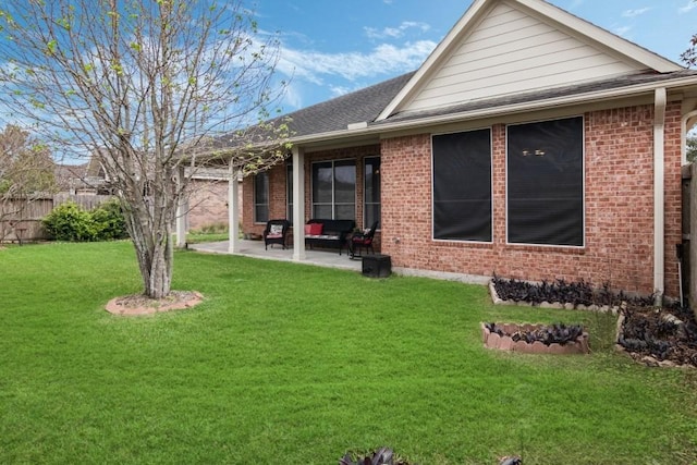 back of house featuring a patio area, brick siding, a yard, and fence